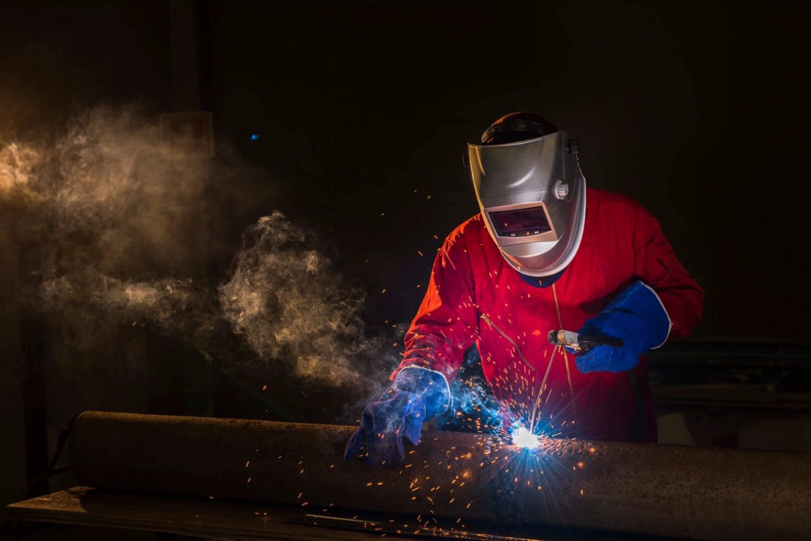 a man wearing a red gear welding a steel